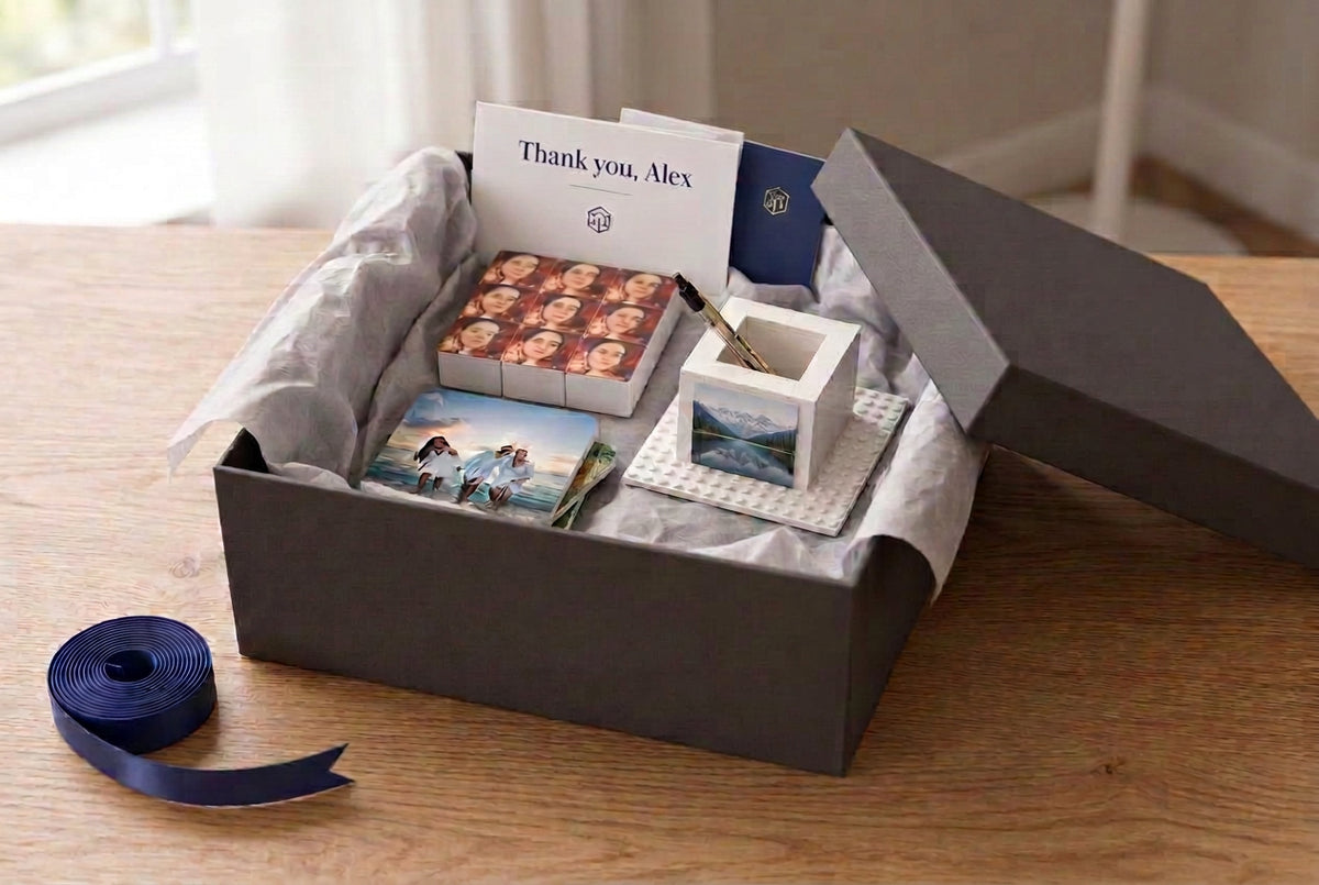 Corporate gift hamper with flat Snap Stack 1x3x3, two photo coasters, photo pen holder and illustrative branded message cards; plain box with navy ribbon beside it